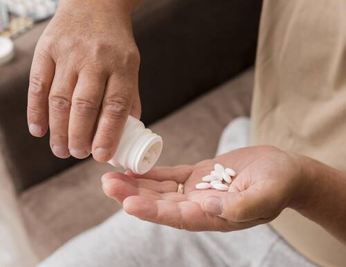 addiction-opioids_close-up-hand-holding-pills