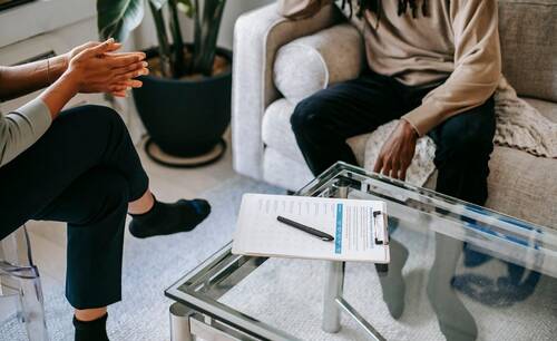 Man sitting on a couch and talking to a therapist.