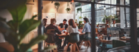 t: A group of individuals seated around a table in a restaurant, engaged in conversation and enjoying their meal.